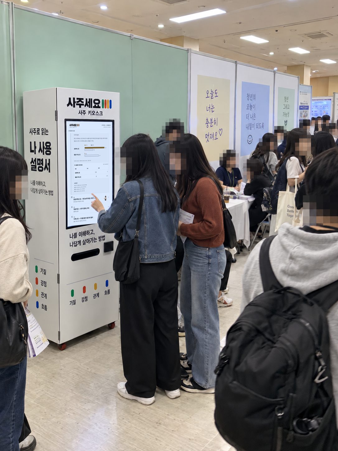 청년 정책 행사에서 참가자들이 사주 자판기 앞에 서 있는 장면