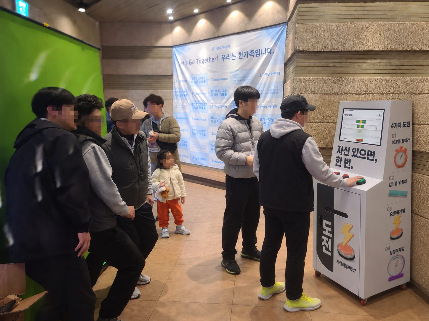 실내 행사장에서 가족 단위 참가자가 감각게임 키오스크의 파워존 게임을 하고 주변에서 지켜보는 장면